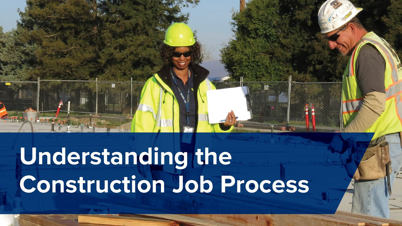 Man and woman in hardhats stand at a construction site