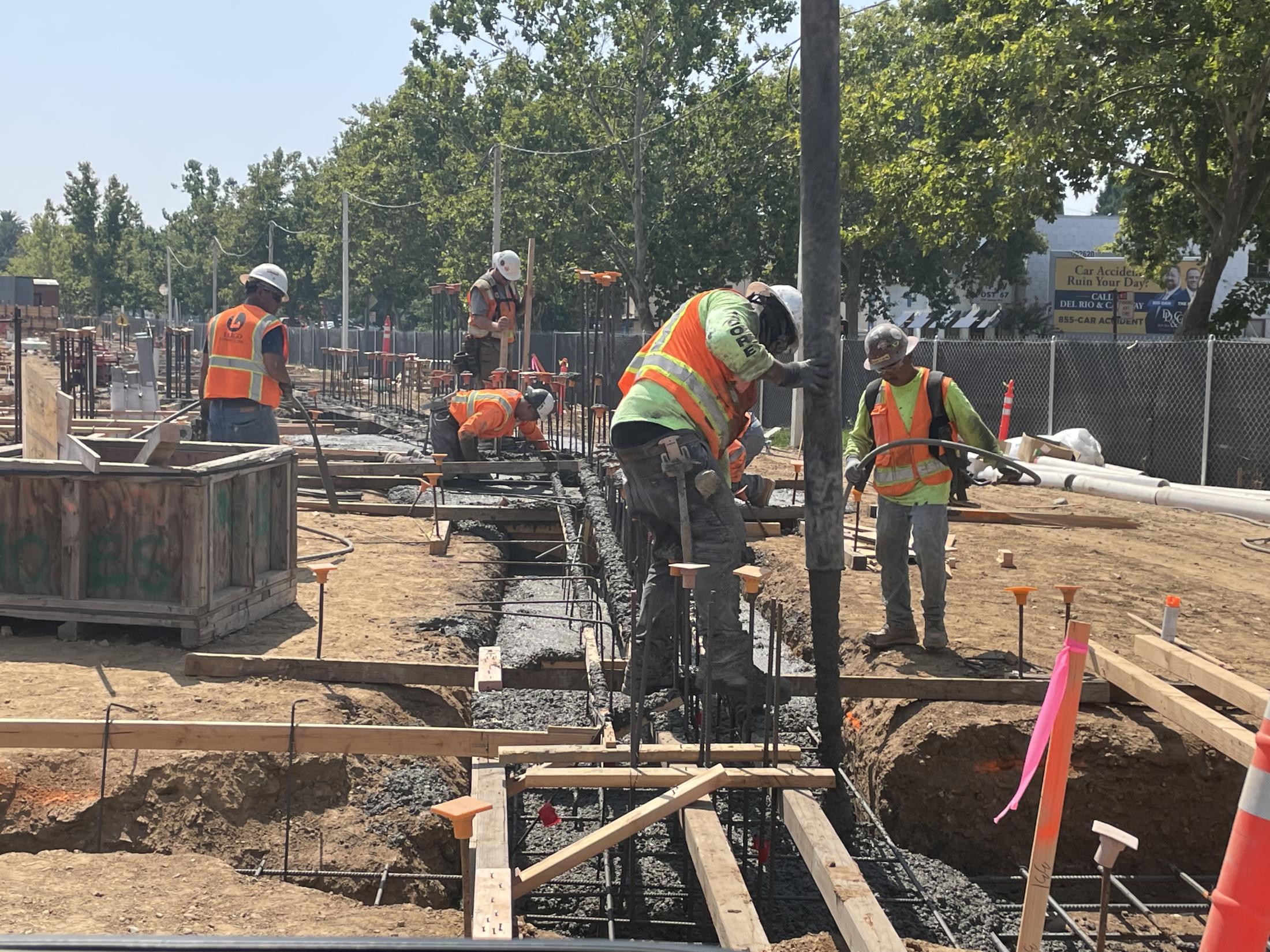 Construction workers pour cement for building footings.