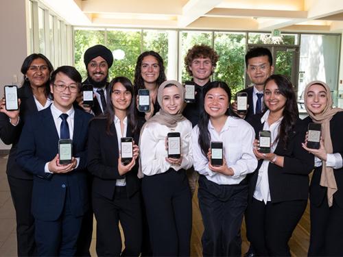 A group of students posing for a picture while holding up phones