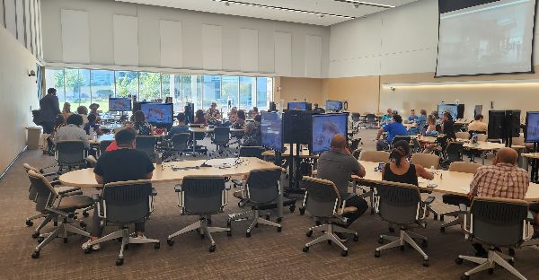 Room full of people sitting at tables with screens