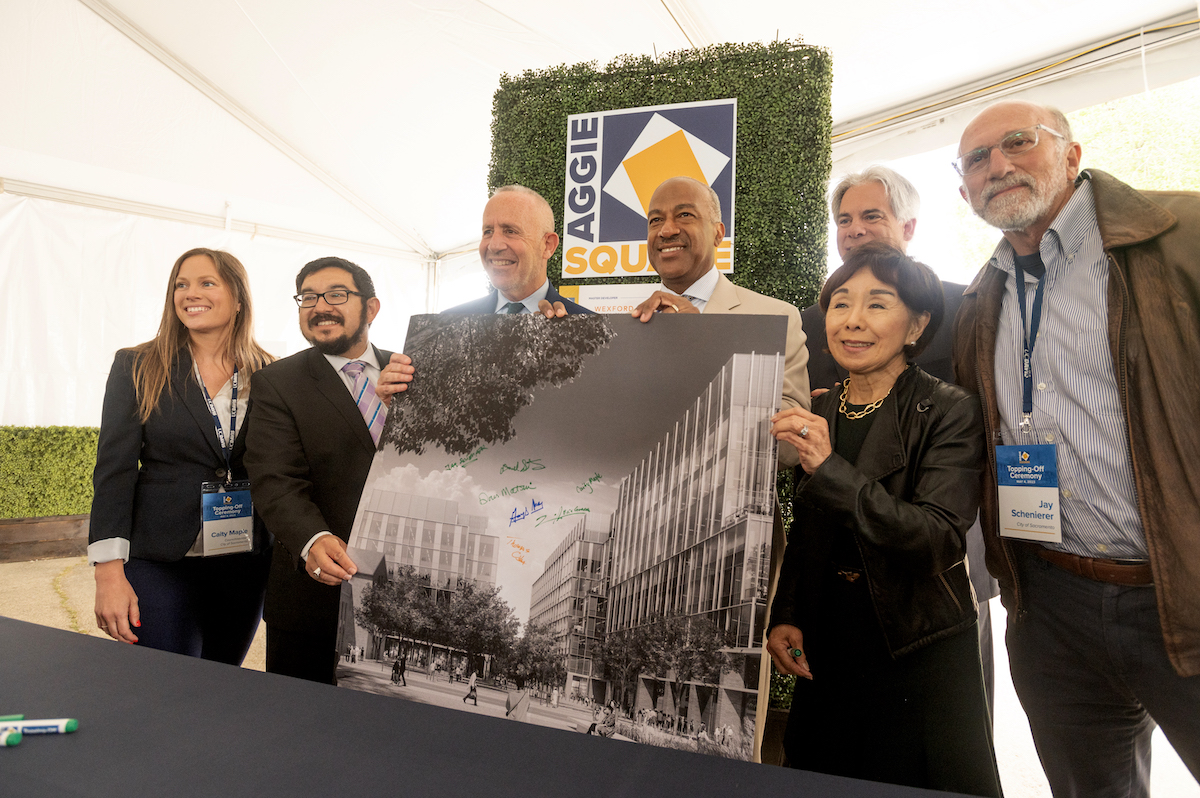 6 people pose for a photo with a signed poster