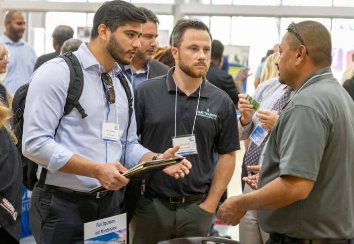 Three men talk amongst each other at an event