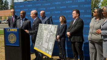 Chancellor May and Mayor Stienberg speak in front of a podium, with other collaborators on either side of them.