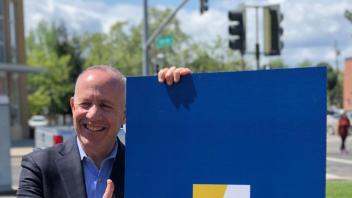 Mayor Steinberg poses for a photo next to the Aggie Square poster on the UC Davis Health campus.