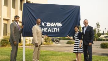 Jason Zachariah, Gary May, Doris Matsui and Darrell Steinberg stand in front of a covered billboard.