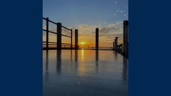 sun rising over construction site, with reflective material that looks similar to a body of water