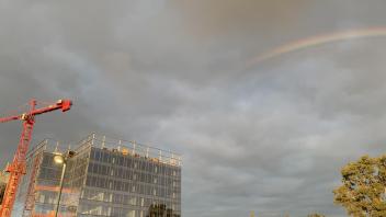 A gray sky with a rainbow over a building