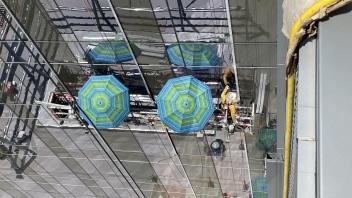 Top-down view of a construction worker working on windows using a window cleaning system and umbrellas to stay out of the sunlight