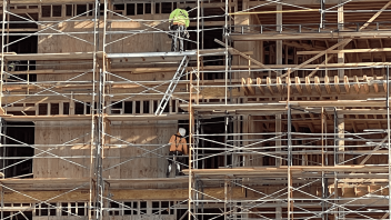 Four construction workers perfectly align vertically on different levels of a building