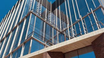A bottom-up view of a building with glass and brick