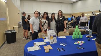 A group of 4 people pose for a picture in front of a table