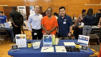 Three people pose for a photo behind a table with the words UC Davis Health