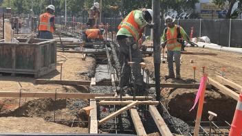 Construction workers pour cement for building footings.