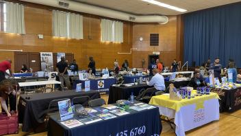 A room of several tables with people walking by and sitting at the tables