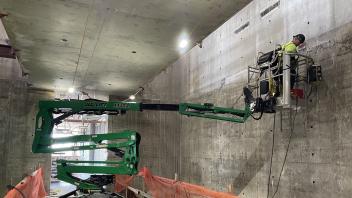 A construction worker works on a crane on the interior of a buildings
