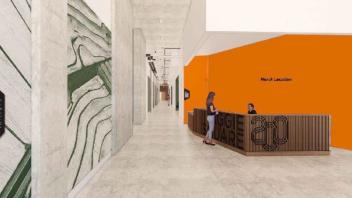 A hallway with a reception desk where two people talk
