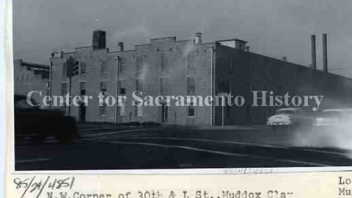 Black and white photo of a factory. Text written by a typewriter says" N.W. Corner of 30th & L St.. Muddox Clay Products since 1905.. Picture. Jan 18, 1963.