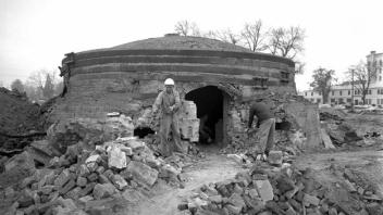 Black and white photo of a person outside a brick kiln with a domed roof.