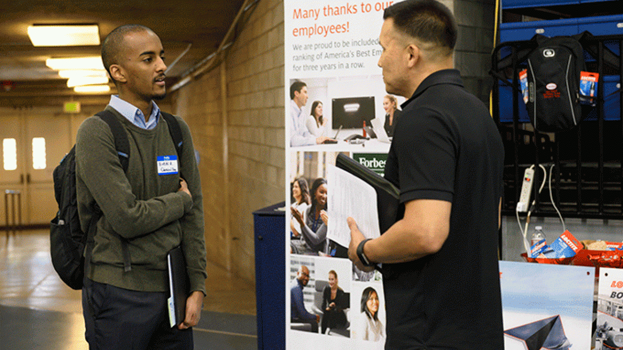 Two people talk at a UC Davis job fair
