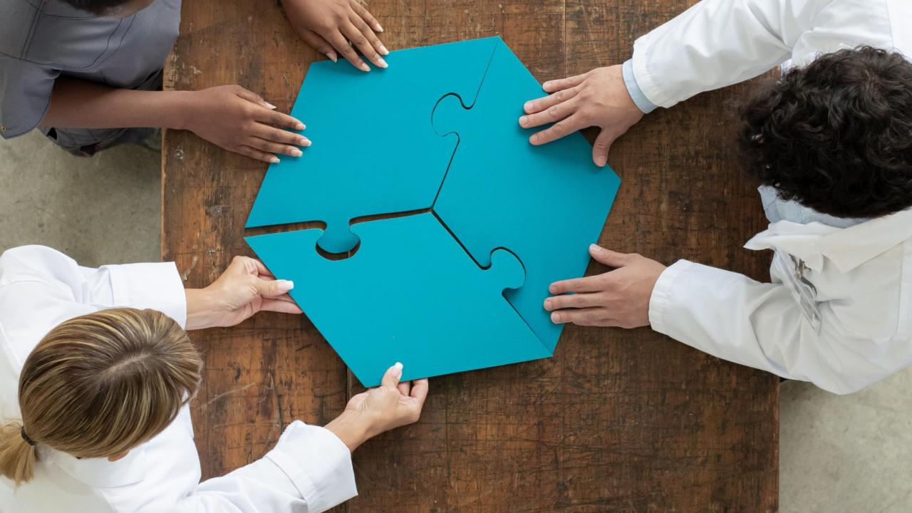 Three people each hold a big piece of puzzle
