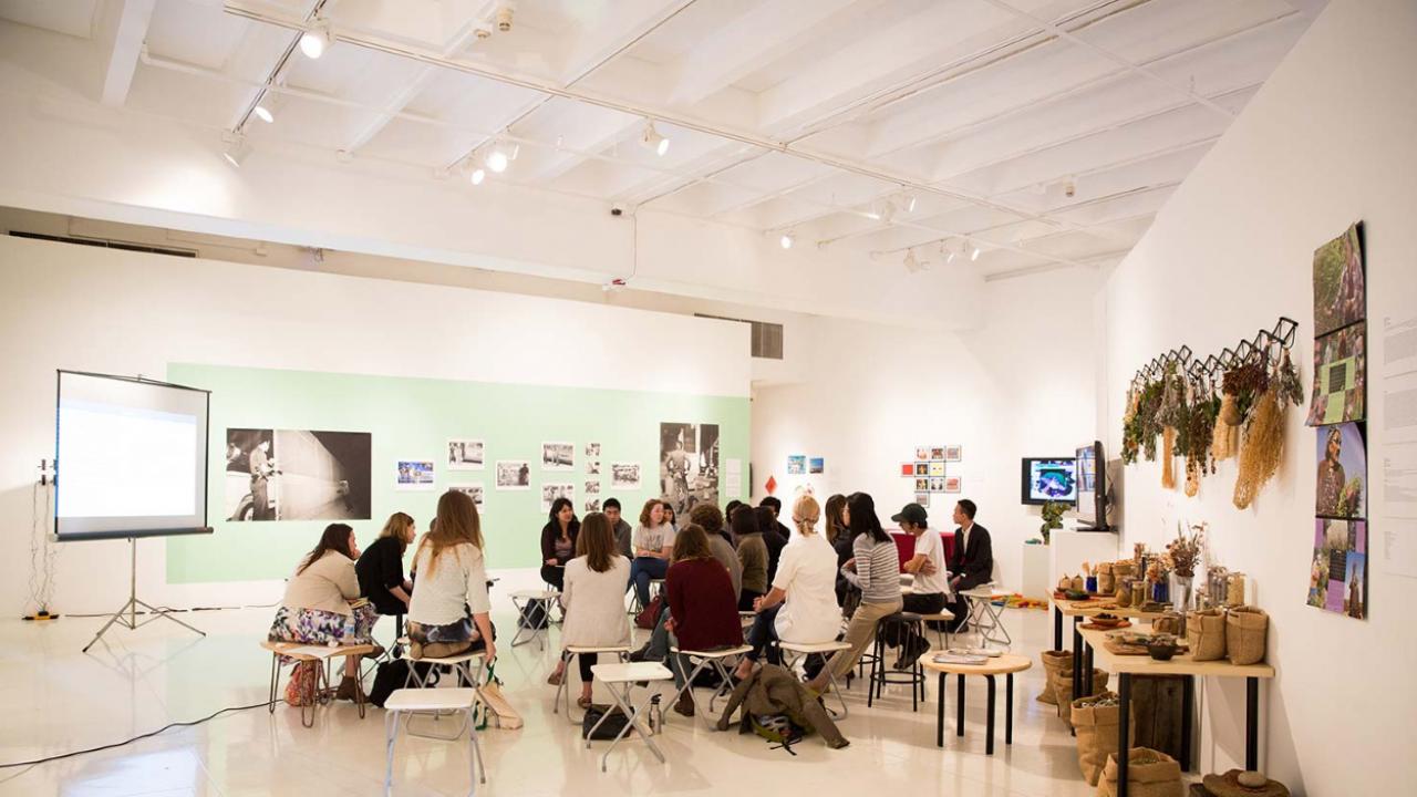 A meeting room with people sitting on stools