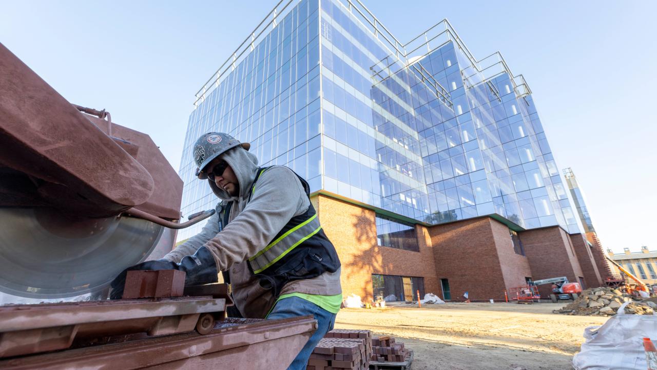A construction worker sawing brick with a building in the background