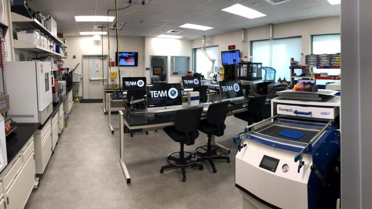 A science lab with various machines and computers that display the TEAM Lab logo