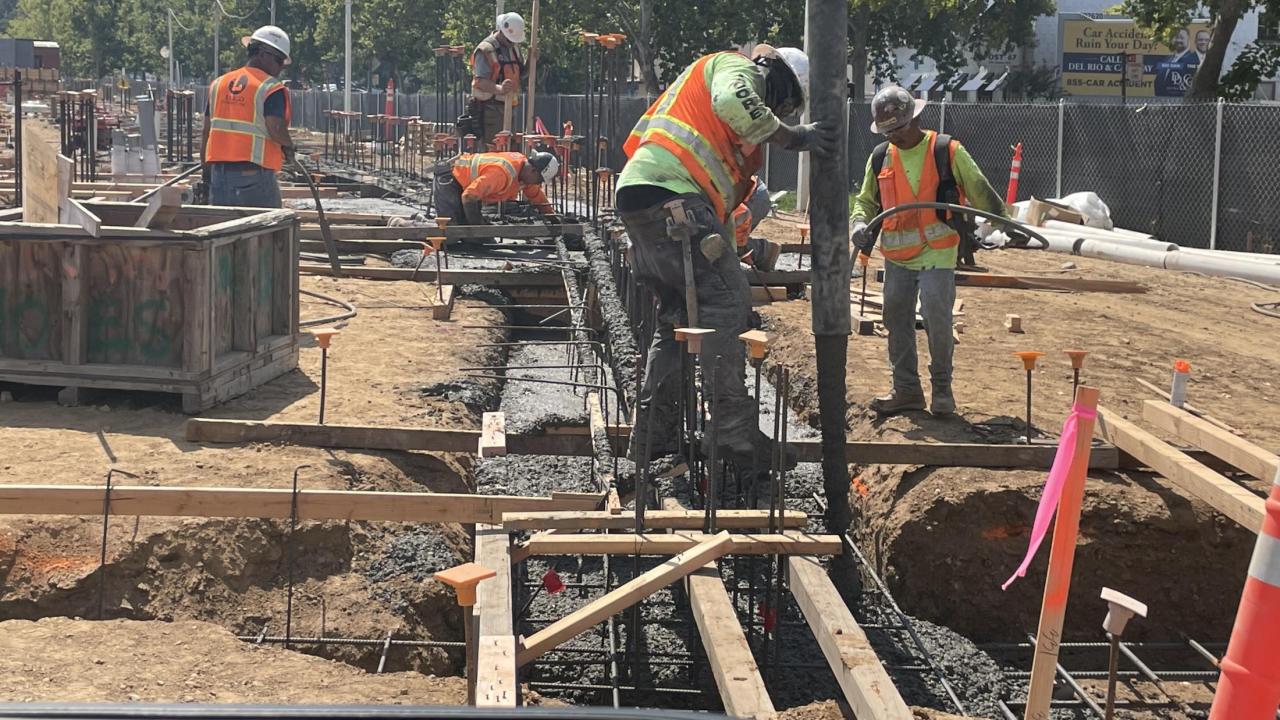 Construction workers pour cement for building footings.