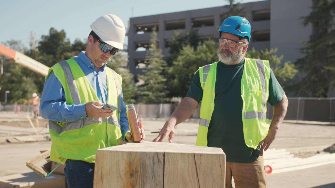 Two construction workers talk together in front of construction