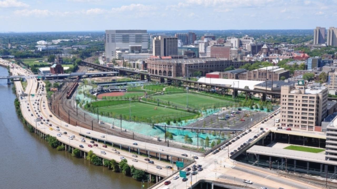 a green sports field next to roadways and a river