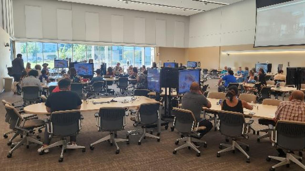 Image of a classroom with individuals at modular table looking at screens.