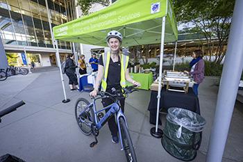 image of woman next to bright green pop-up tent with helmet, green vest and bike.