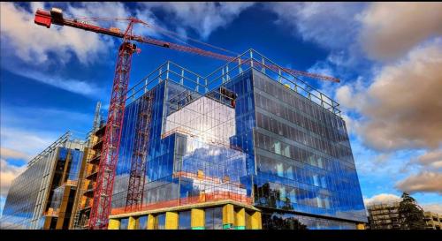 A building with glass windows that reflects the blue sky and clouds