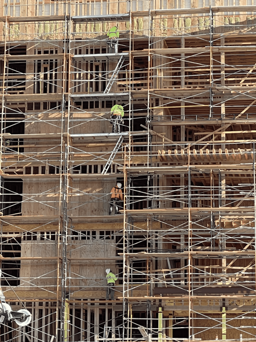 Four construction workers perfectly align vertically on different levels of a building