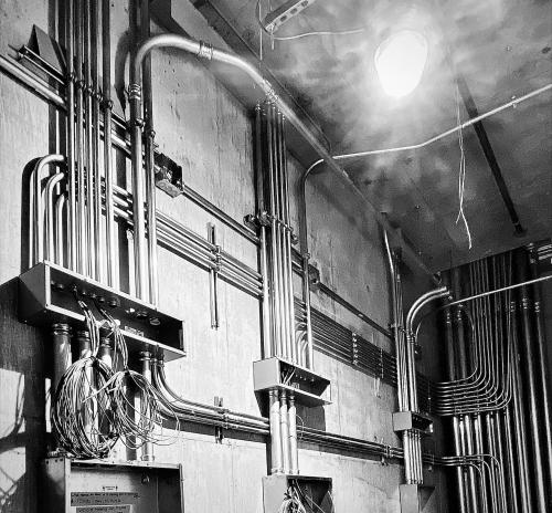 Black and white image of steel pipe management for wires and cables.