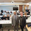 Two men in the front of a classroom posed for a photo with class