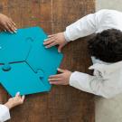 Three people each hold a big piece of puzzle