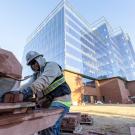 A construction worker sawing brick with a building in the background