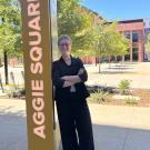 Bailey Day leans against a pillar that reads "Aggie Square"
