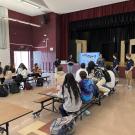 A group of students in a cafeteria listening to a presenter
