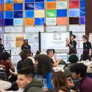 Four students stand in the front of a room of students presenting about Aggie Square