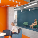 Rendering of an open office space with two people talking at a table and one person walking in through the door