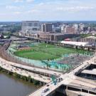 a green sports field next to roadways and a river