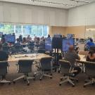 Image of a classroom with individuals at modular table looking at screens.