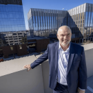 George Baxter poses for photo with Aggie Square buildings in background.