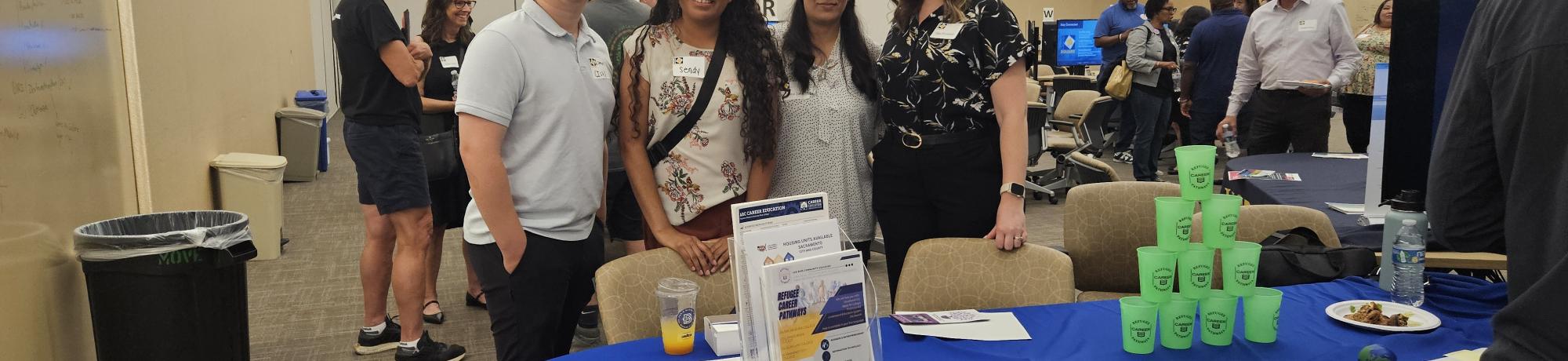 A group of 4 people pose for a picture in front of a table