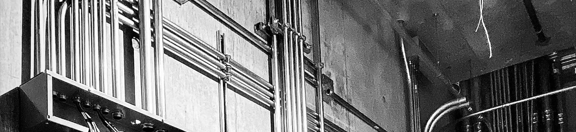 Black and white image of steel pipe management for wires and cables.