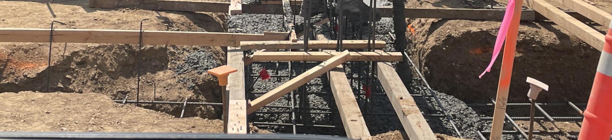 Construction workers pour cement for building footings.